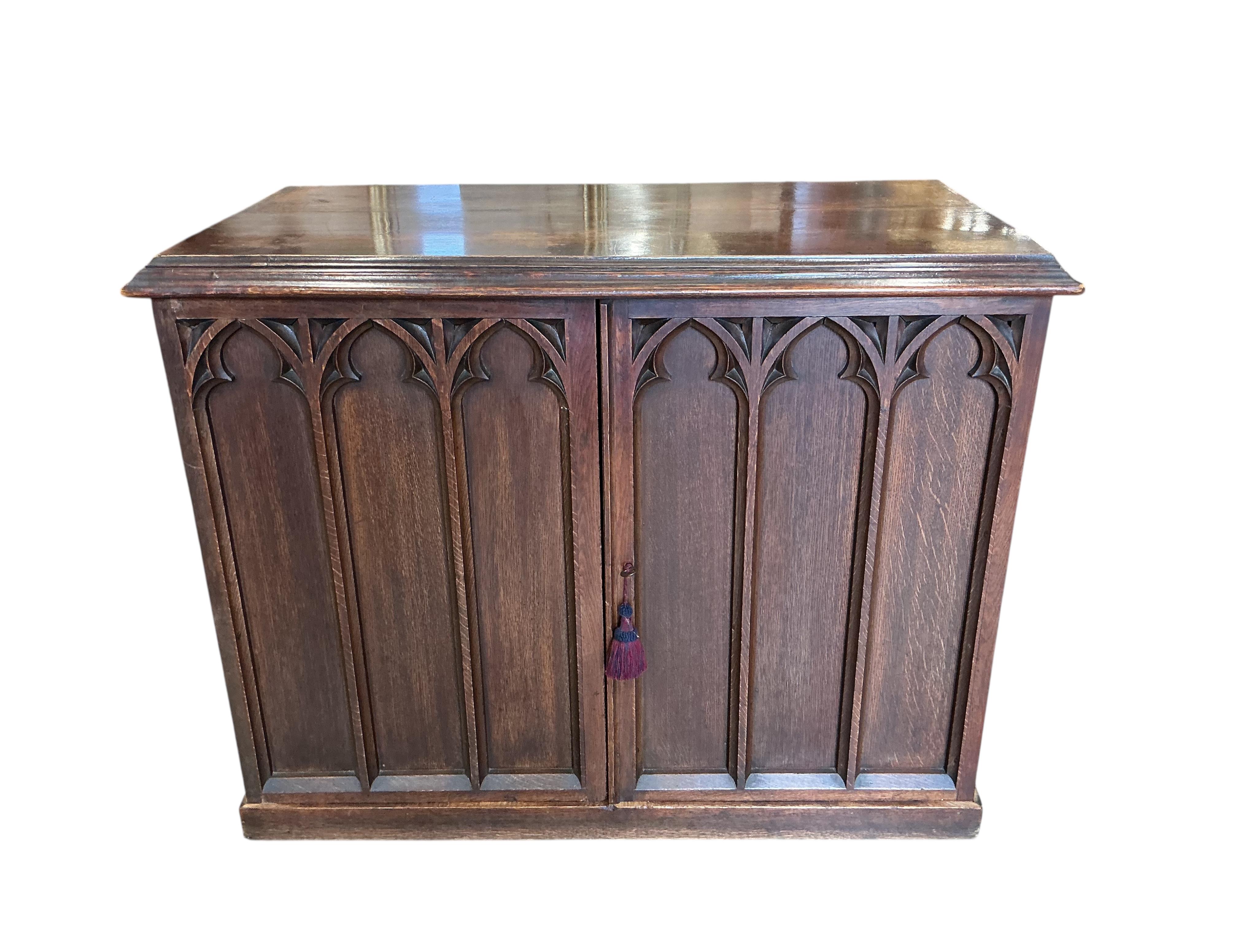 A late Victorian Gothic style oak two door side cabinet, width 122cm, depth 62cm, height 94cm
